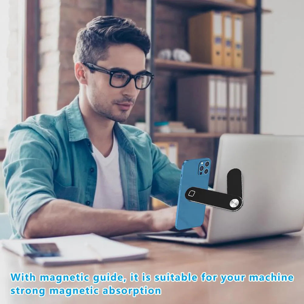 Black aluminium laptop phone holder with magnetic clip attached to a laptop screen, holding a smartphone.