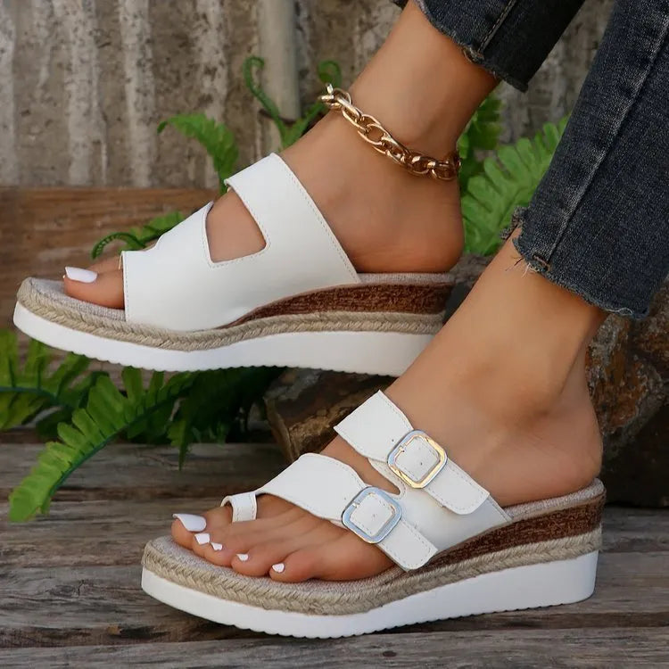 White patent leather women's wedge sandals with a woven design and peep toe on a rubber sole.