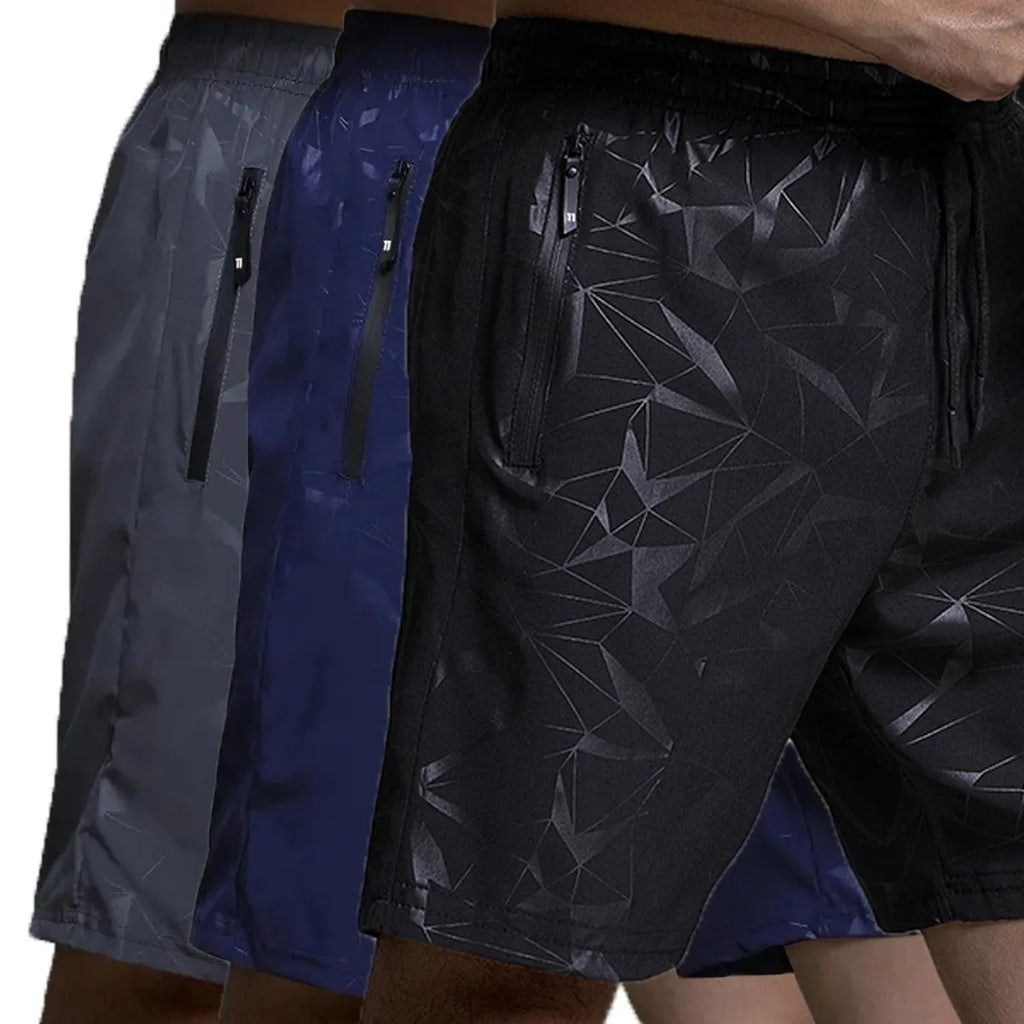 Man wearing loose fit black printed polyester sports shorts with elastic waistband on a beach.