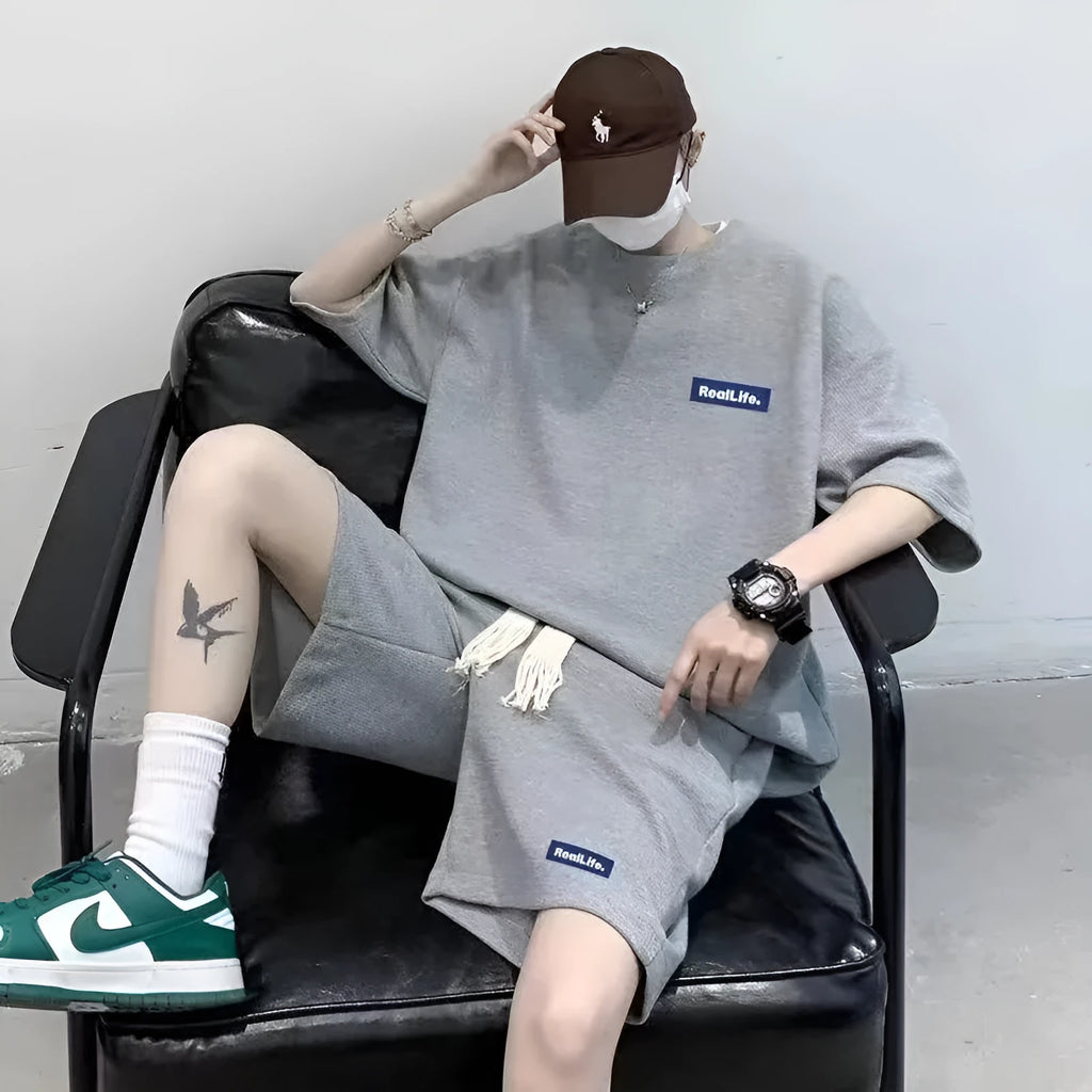 Man wearing a grey waffle-textured cotton blend short sleeve top and matching shorts leisure set.