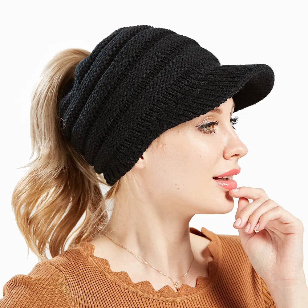 Woman wearing a thick knitted beanie with a ponytail threaded through the hole in the crown.