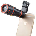 Black 12x mobile phone telescope lens with clip extended next to smartphone