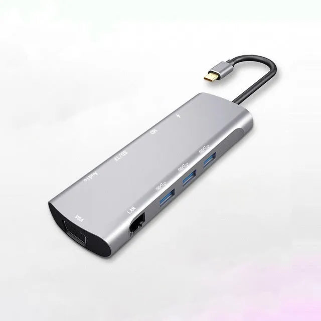 Grey aluminium USB-C docking station showing HDMI, VGA, USB 3.0, and USB-C PD ports with a short attached cable.