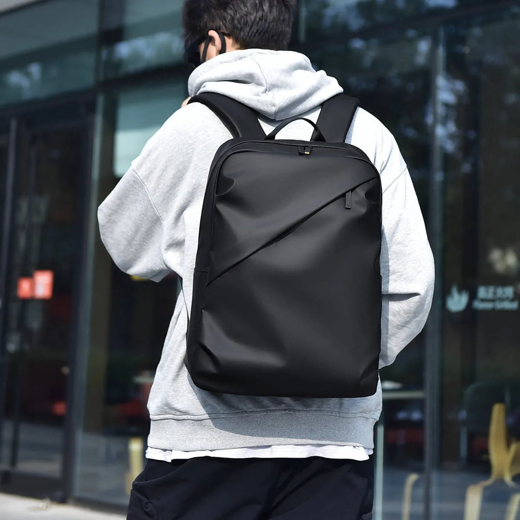 Large waterproof backpack in black with sewing thread detailing and included computer bag