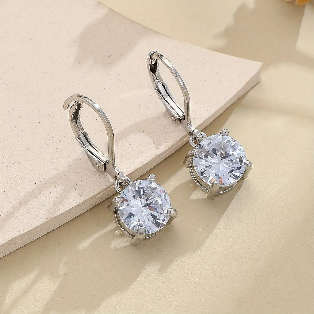 Silver colour zircon earrings with genuine stones and secure metal fastening on a white background
