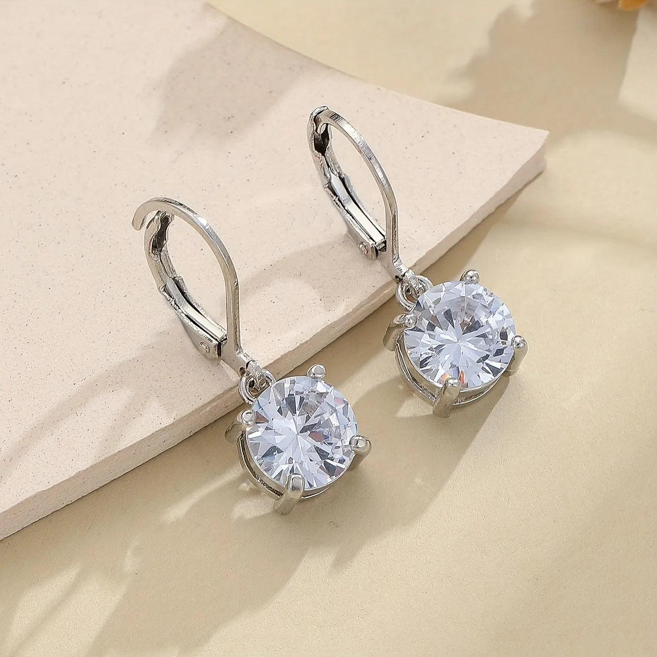 Silver colour zircon earrings with genuine stones and secure metal fastening on a white background