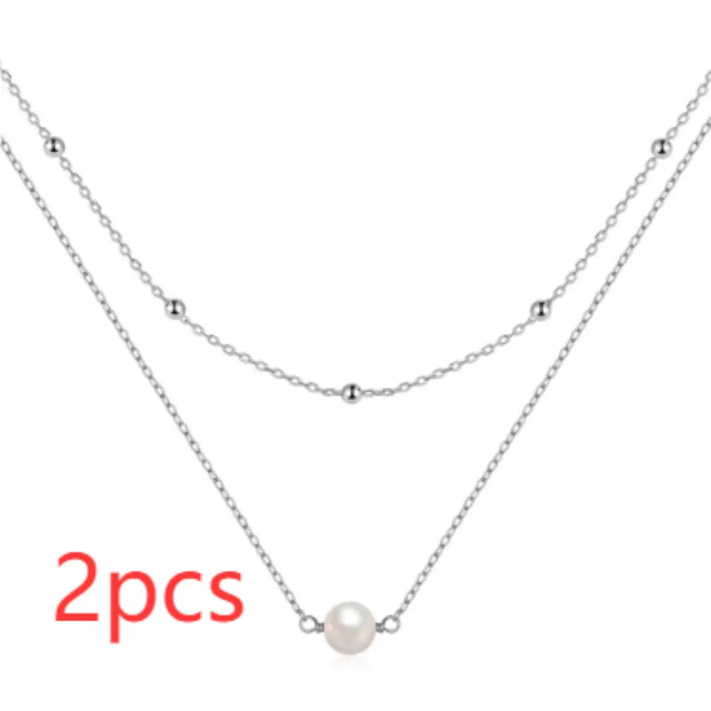 Close-up of a sterling silver double layer necklace with twin pearls on a ball bead chain, shown in gold tone.