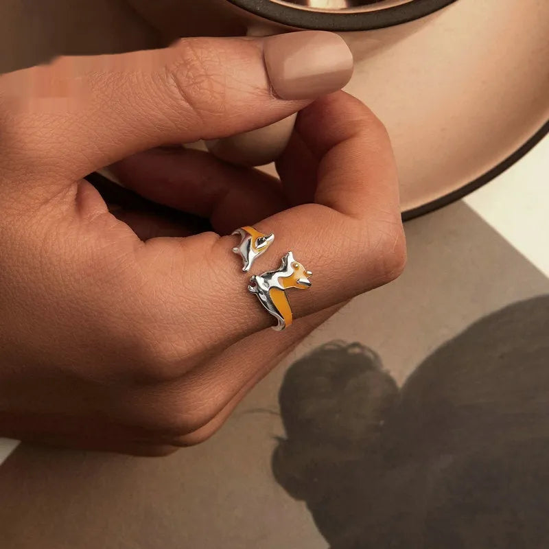 Silver-coloured cartoon corgi dog ring for women on a plain background.