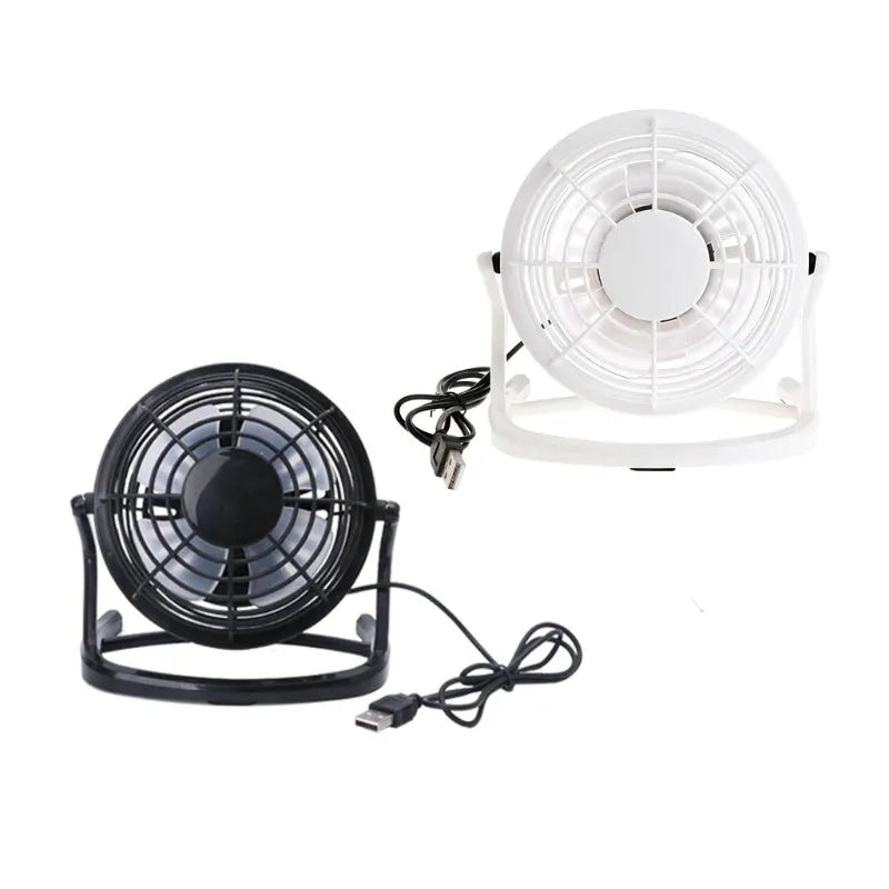 Small black USB desk fan with adjustable angle on wooden desk next to laptop
