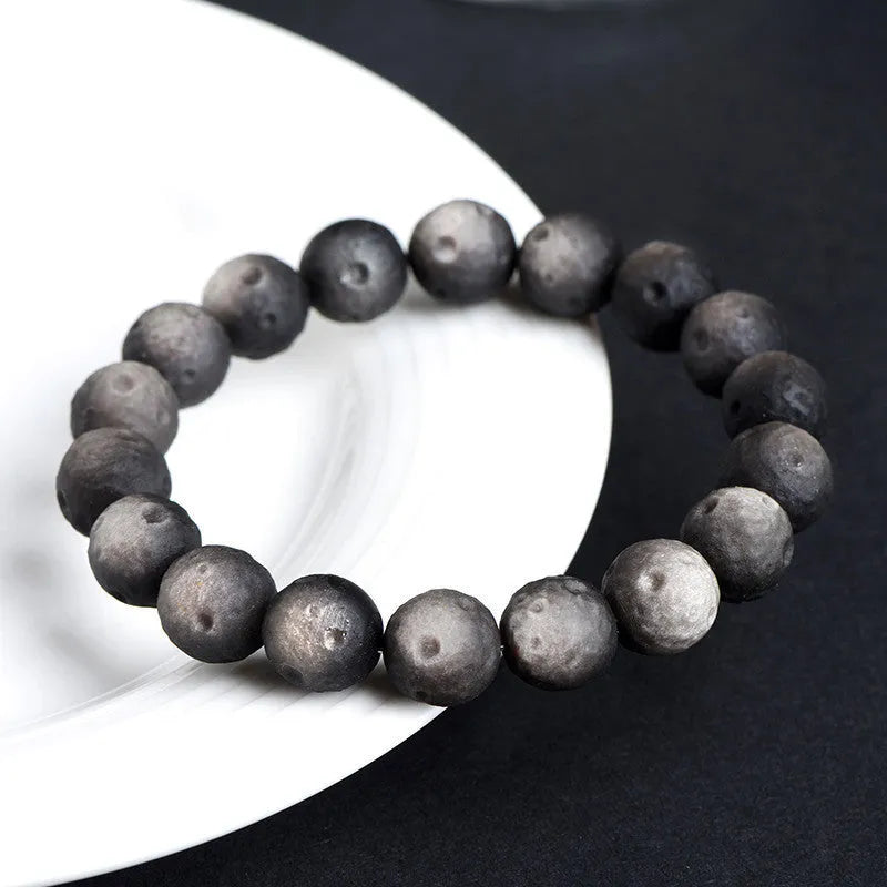 Natural obsidian crater ball bracelet showing textured beads in silver stone or golden obsidian colour on a wrist.