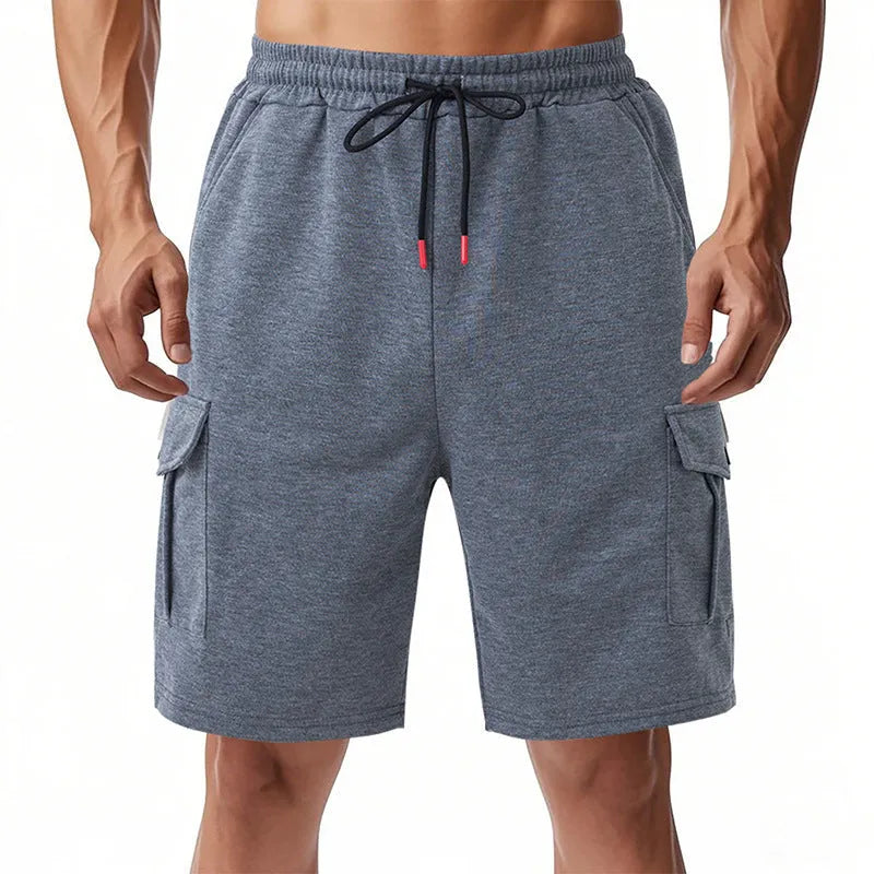 Man wearing heavy grey loose-fit cargo sports shorts with multiple pockets, made from terry towel fabric.