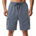 Man wearing heavy grey loose-fit cargo sports shorts with multiple pockets, made from terry towel fabric.