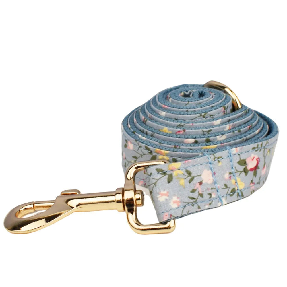 Blue floral patterned cloth dog collar with matching leash and vest set on a white background.