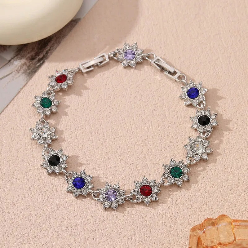 Electroplated zinc alloy bracelet with flower-shaped coloured gems in gold or silver tone.