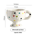 Hand-pinched irregular shaped ceramic mug in a solid colour, shown on a table.