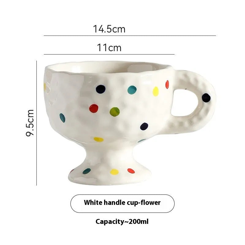 Hand-pinched irregular shaped ceramic mug in a solid colour, shown on a table.