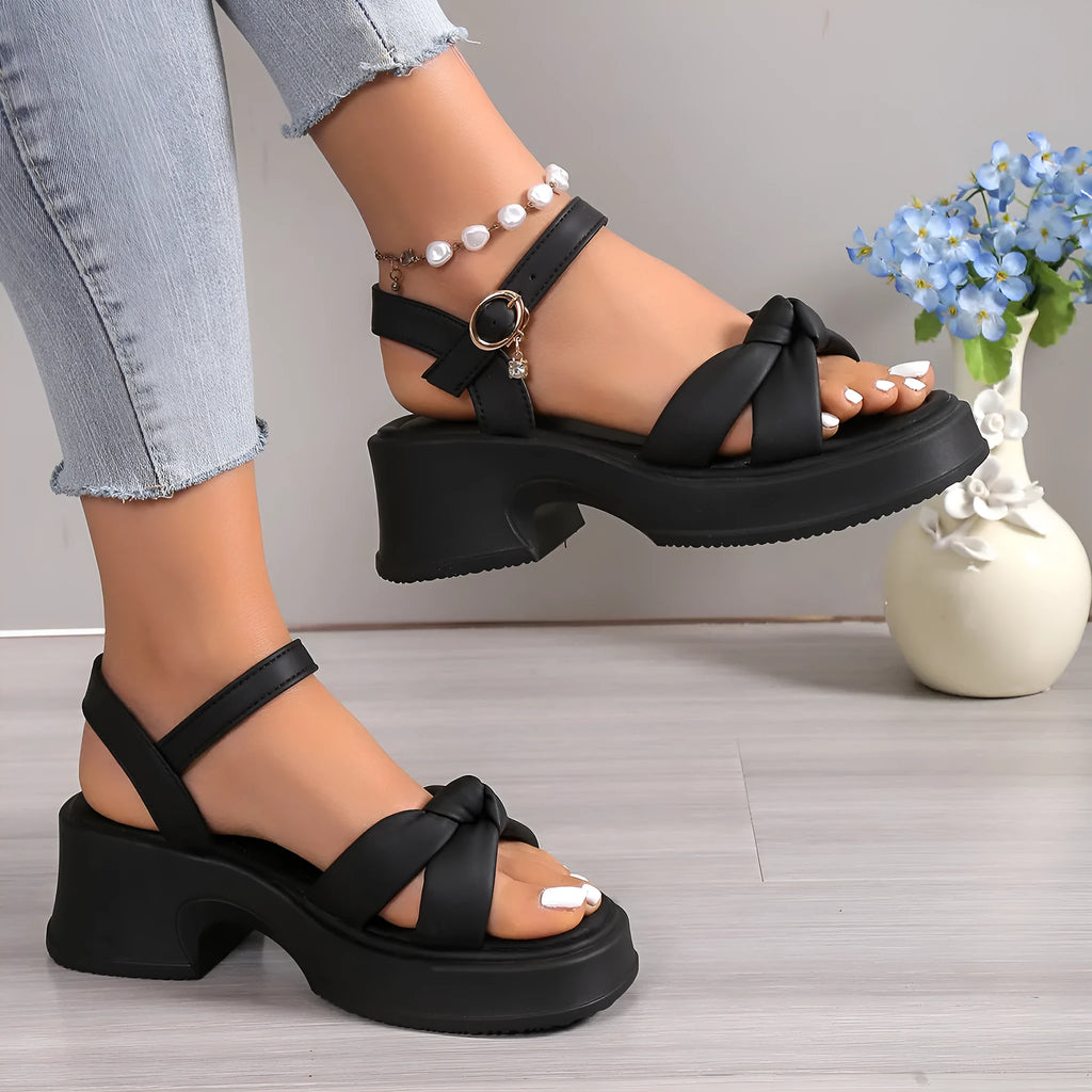 Women's black thick-heel slippers with a decorative skirt detail and button fastening.