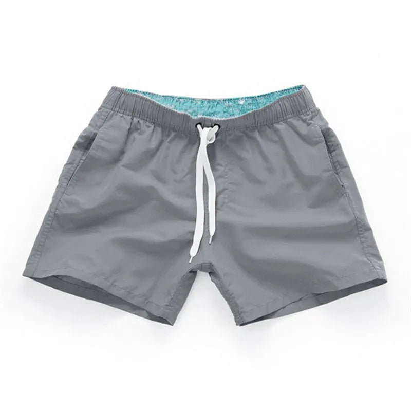 Men's straight-leg polyester beach shorts on a hanger, showing the classic fit and available in multiple solid colours.