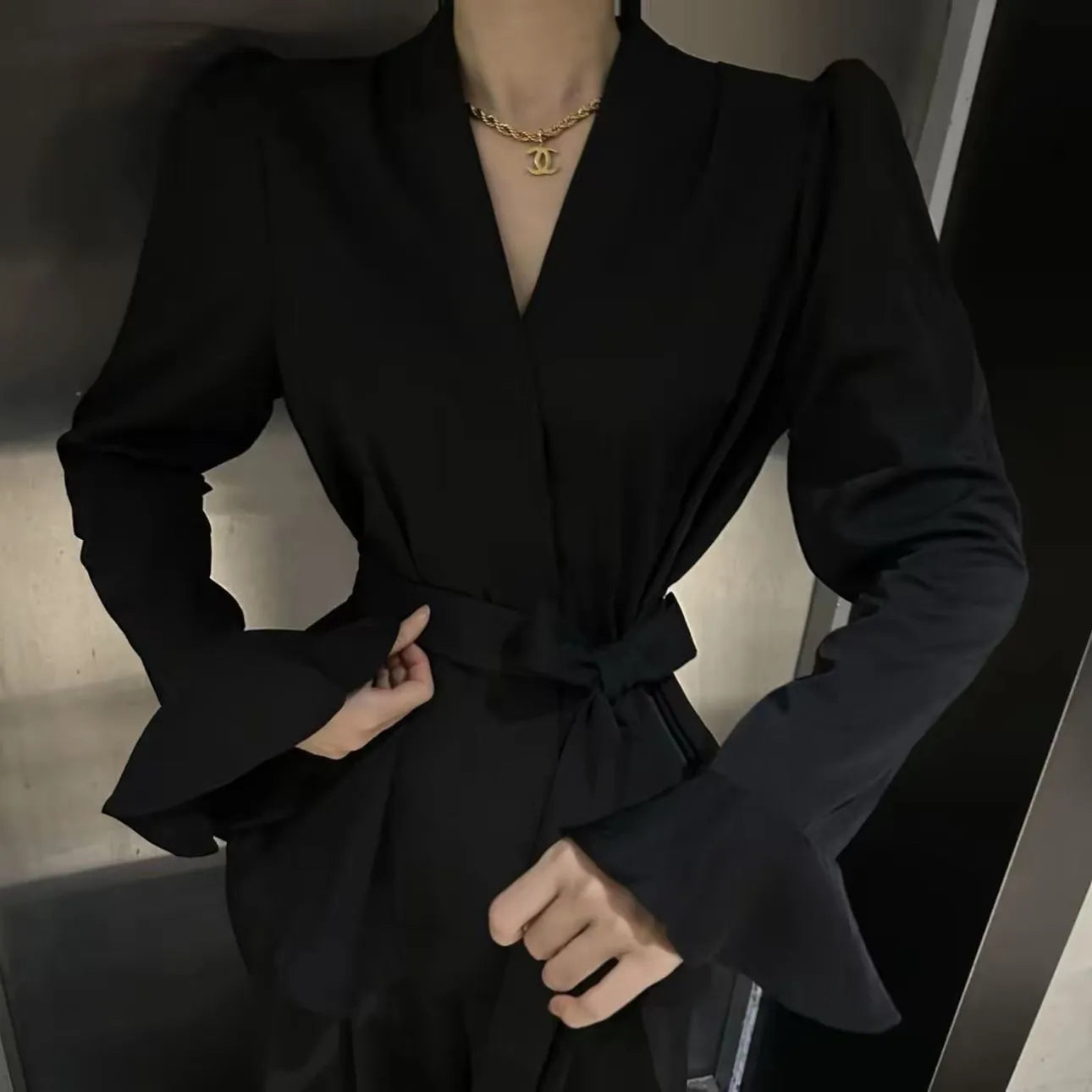 Women's black French-style shirt with irregular collar and tied waist detail featuring bell sleeves