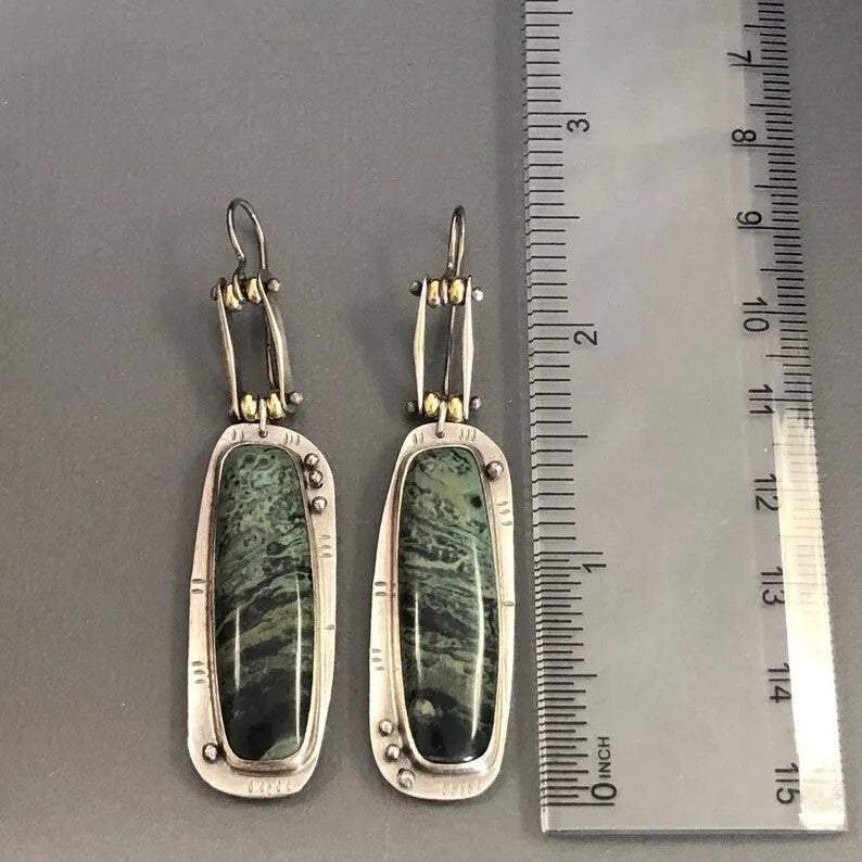 Geometric alloy earrings with a white and grey marble pattern on a simple background.