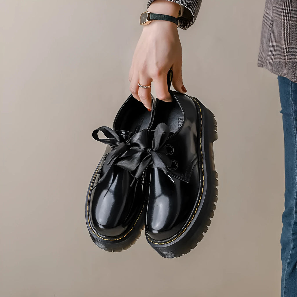 Women's black leather lace-up shoes with thick soles and cross-strap ribbons on the upper.