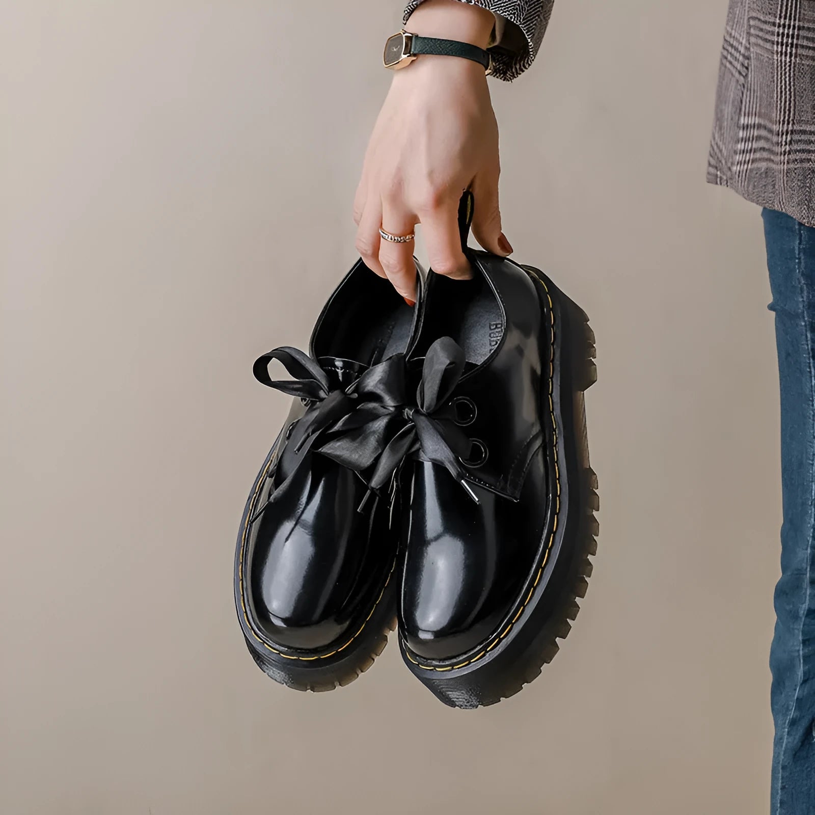 Women's black leather lace-up shoes with thick soles and cross-strap ribbons on the upper.