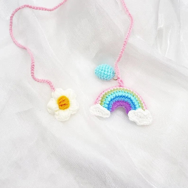 Handmade crocheted wool car pendant with a cartoon flower in avocado, pink rainbow, or red rainbow colours.