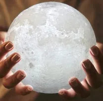 3D printed moon lamp glowing on a wooden stand with touch ring at base