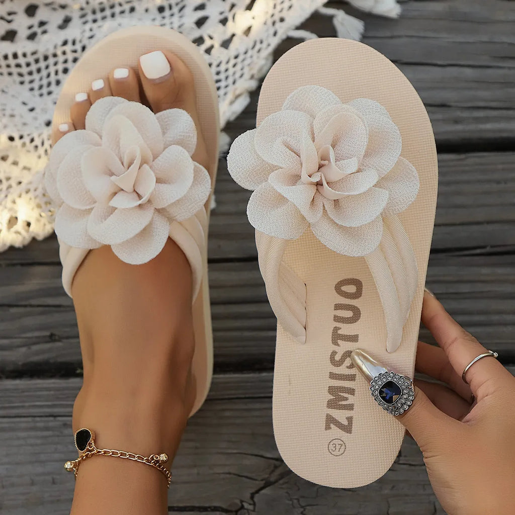 Plus size solid colour flip flop slippers with a flower detail on the upper, shown in beige.