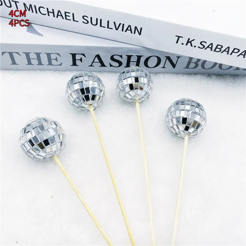 Glass disco ball cake decoration with wooden stick in various sizes on a cake.