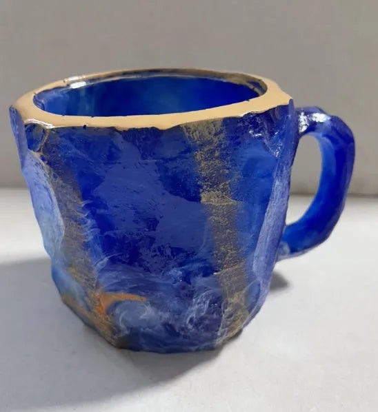 Purple and blue resin coffee mug with crystal texture and handle on wooden table