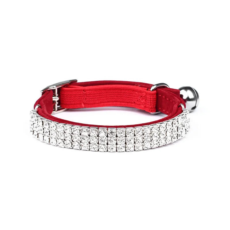 Close-up of a soft red velvet cat collar with a line of sparkling rhinestones and an adjustable buckle.