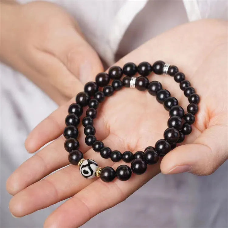 Ebony beaded bracelet with two-circle Tibetan-inspired design on wrist