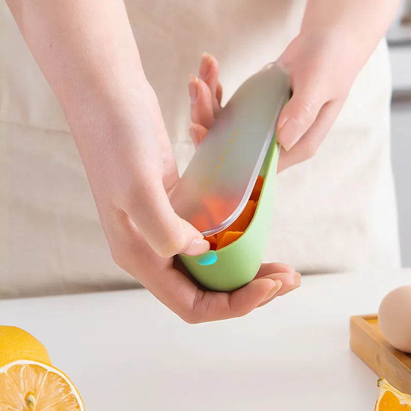 Green vegetable and fruit peeler with a storage tube and stainless steel blade on a kitchen counter.