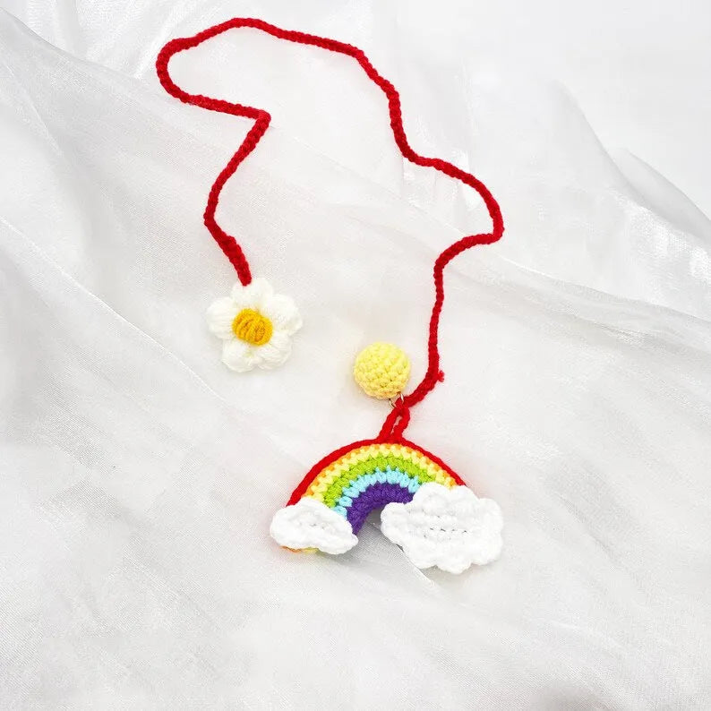 Handmade crocheted wool car pendant with a cartoon flower in avocado, pink rainbow, or red rainbow colours.