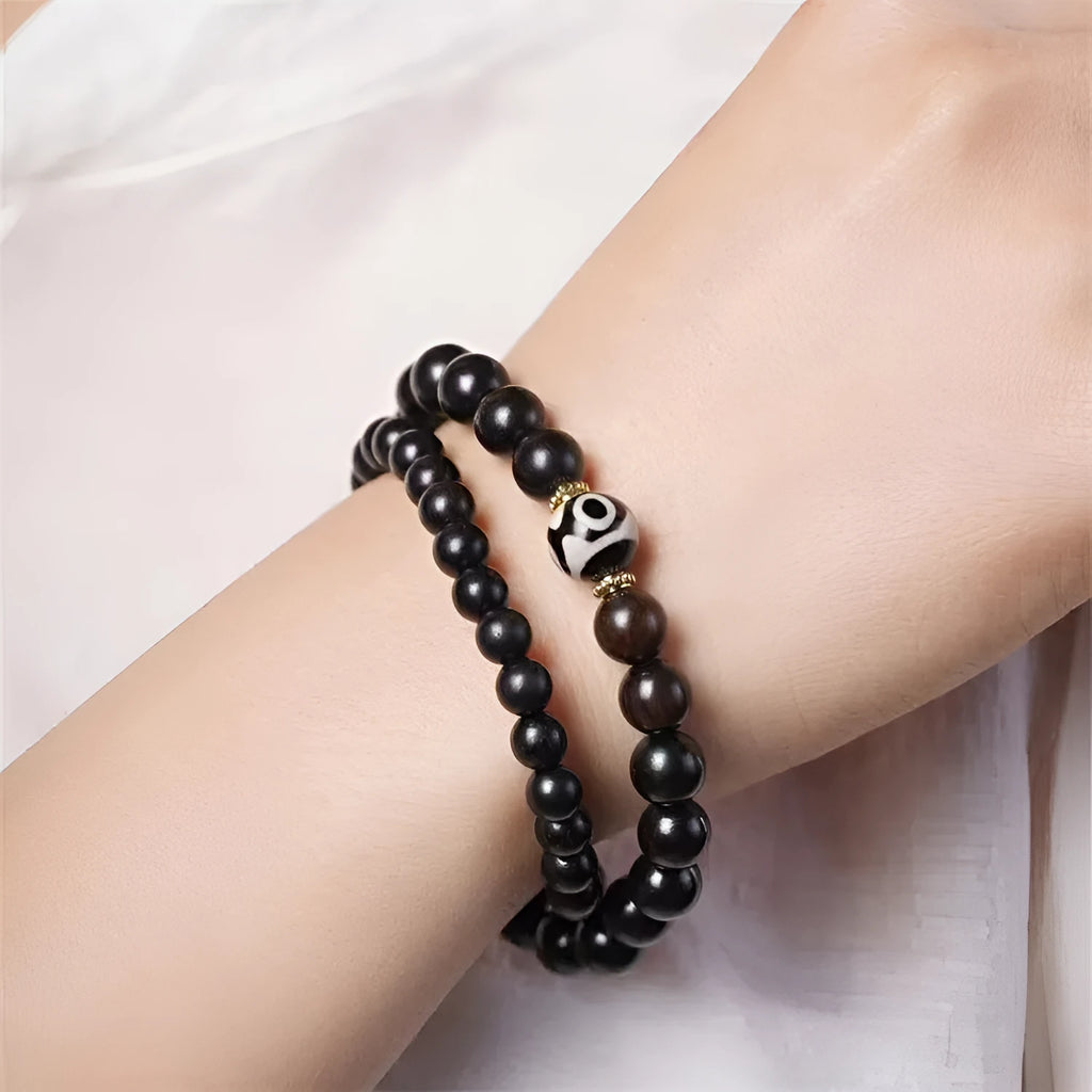 Ebony beaded bracelet with two-circle Tibetan-inspired design on wrist