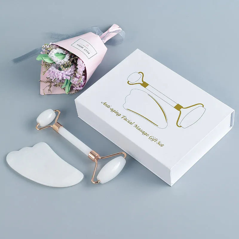 White jade double-headed facial roller and gua sha scraping board set on a neutral background.