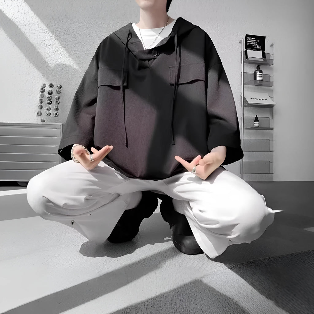 Man wearing a loose-fit black polyester hooded t-shirt with short sleeves.