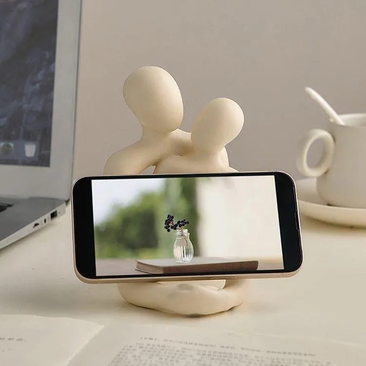 Modern loving couple resin statue in milky white or gold on a bookshelf.