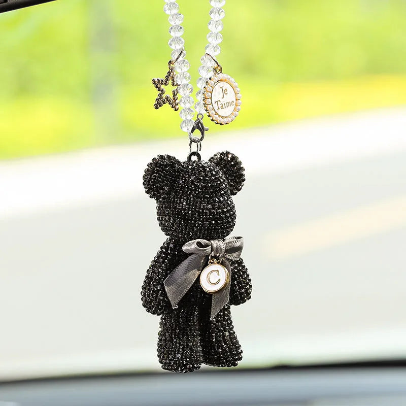 Close-up of a crystal rhinestone Violent Bear ornament on a car rearview mirror.