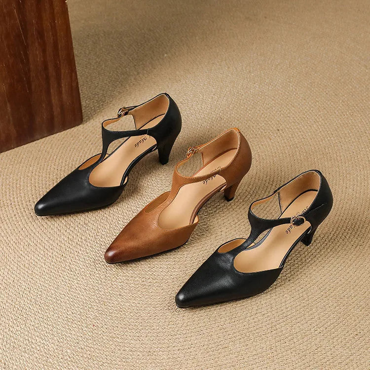 Brown retro women's T-strap closed toe sandals with a stout heel on a wooden surface.