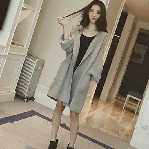 A plus-size woman wearing a loose grey cotton coat with lace details and long sleeves.