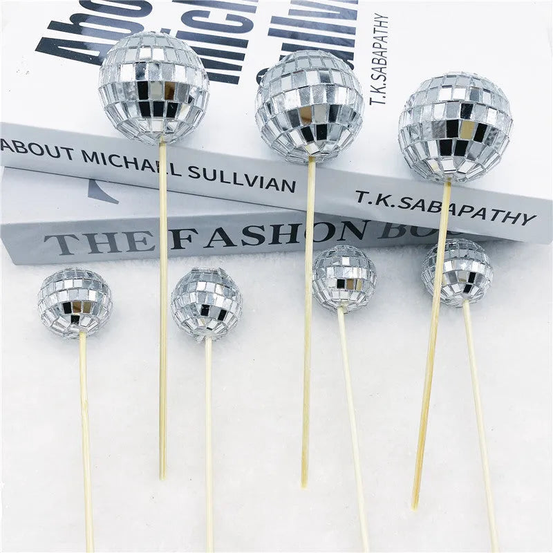 Glass disco ball cake decoration with wooden stick in various sizes on a cake.