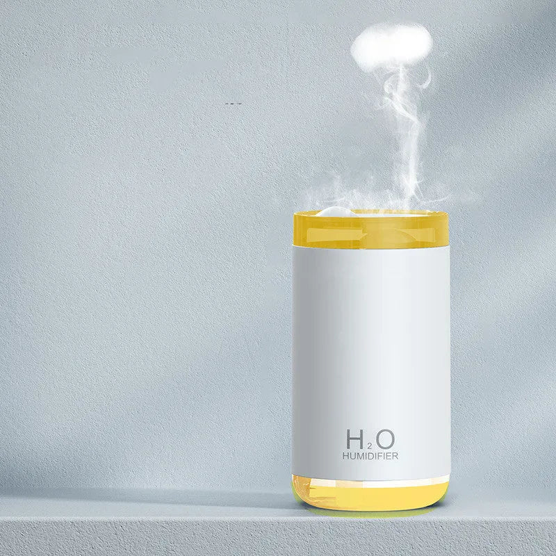 White jellyfish-shaped humidifier emitting smoke rings on a desk, with USB cable and warm glow.