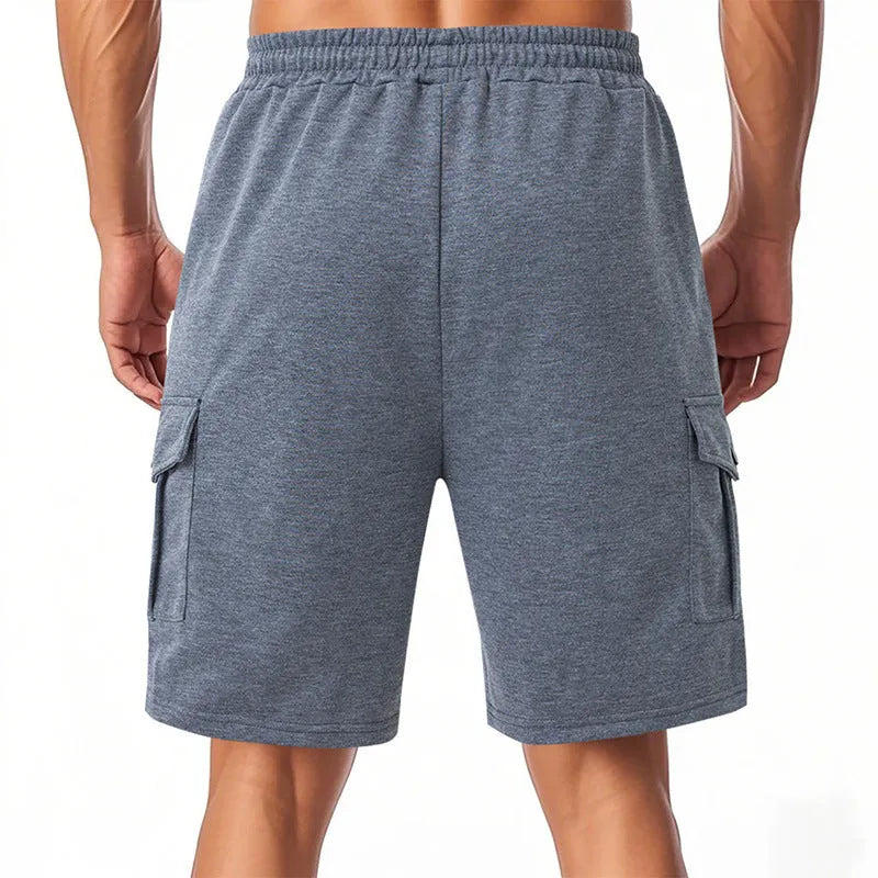 Man wearing heavy grey loose-fit cargo sports shorts with multiple pockets, made from terry towel fabric.