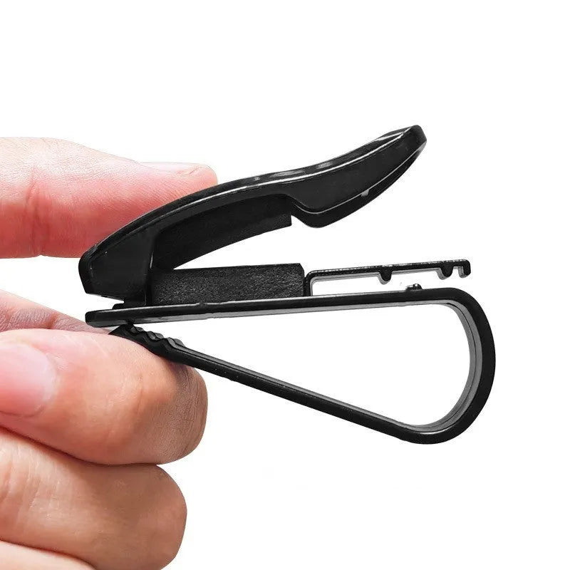 Black plastic multifunctional car mounted glasses and card clip attached to a sun visor holding sunglasses and an ID card