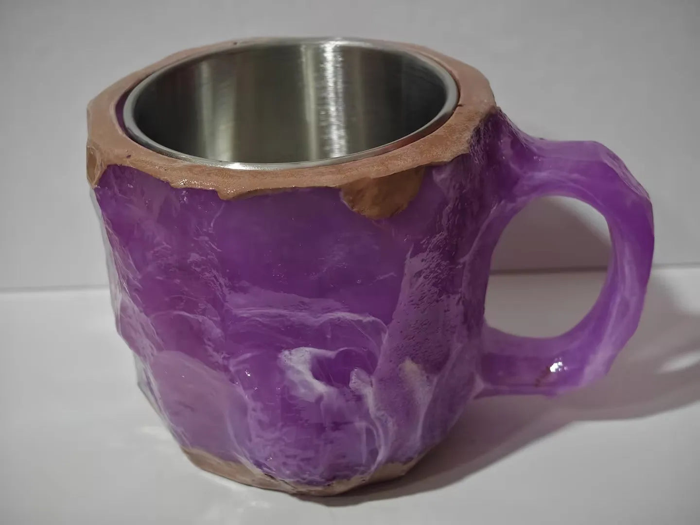 Purple and blue resin coffee mug with crystal texture and handle on wooden table