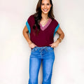 Burgundy women's V-neck sweater with contrast trim and cuffed short sleeves on hanger