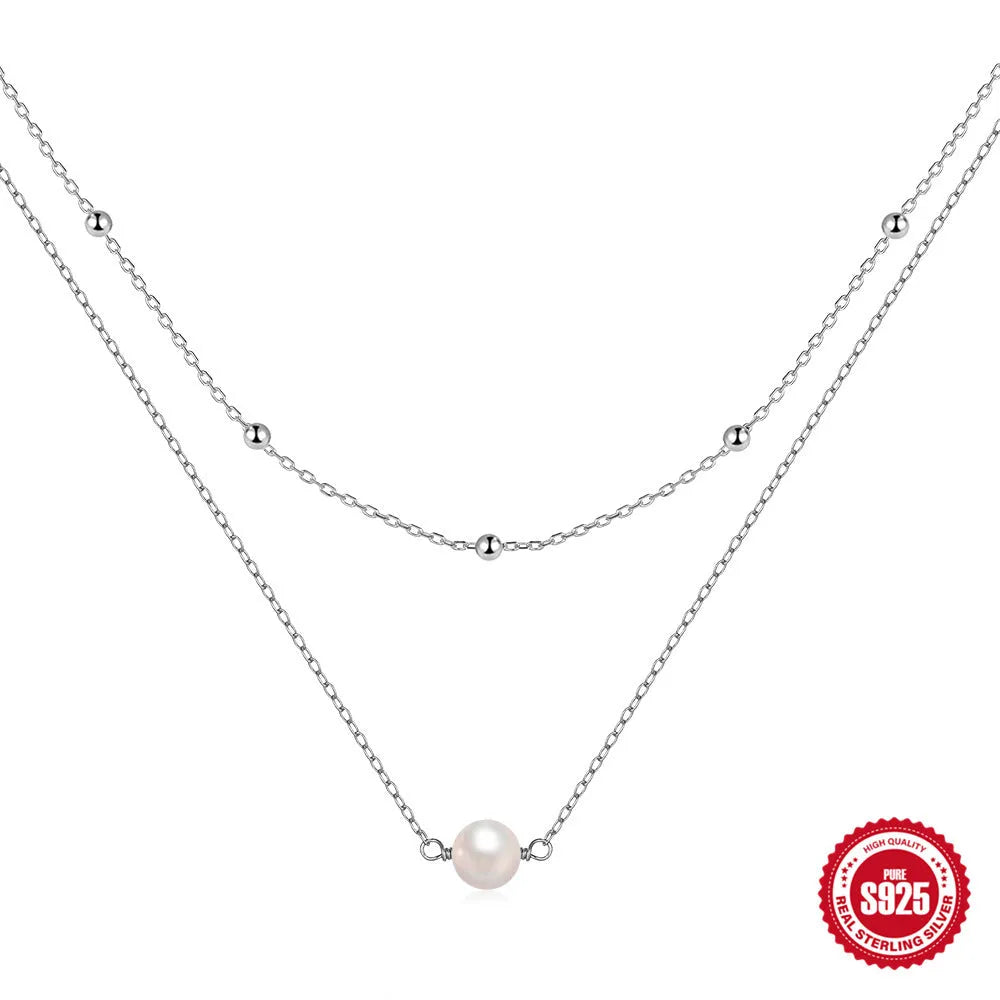 Close-up of a sterling silver double layer necklace with twin pearls on a ball bead chain, shown in gold tone.