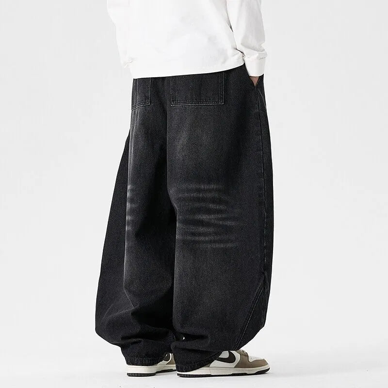 Men's plus-size baggy blue jeans with a wide leg and straight hem on a casual background.